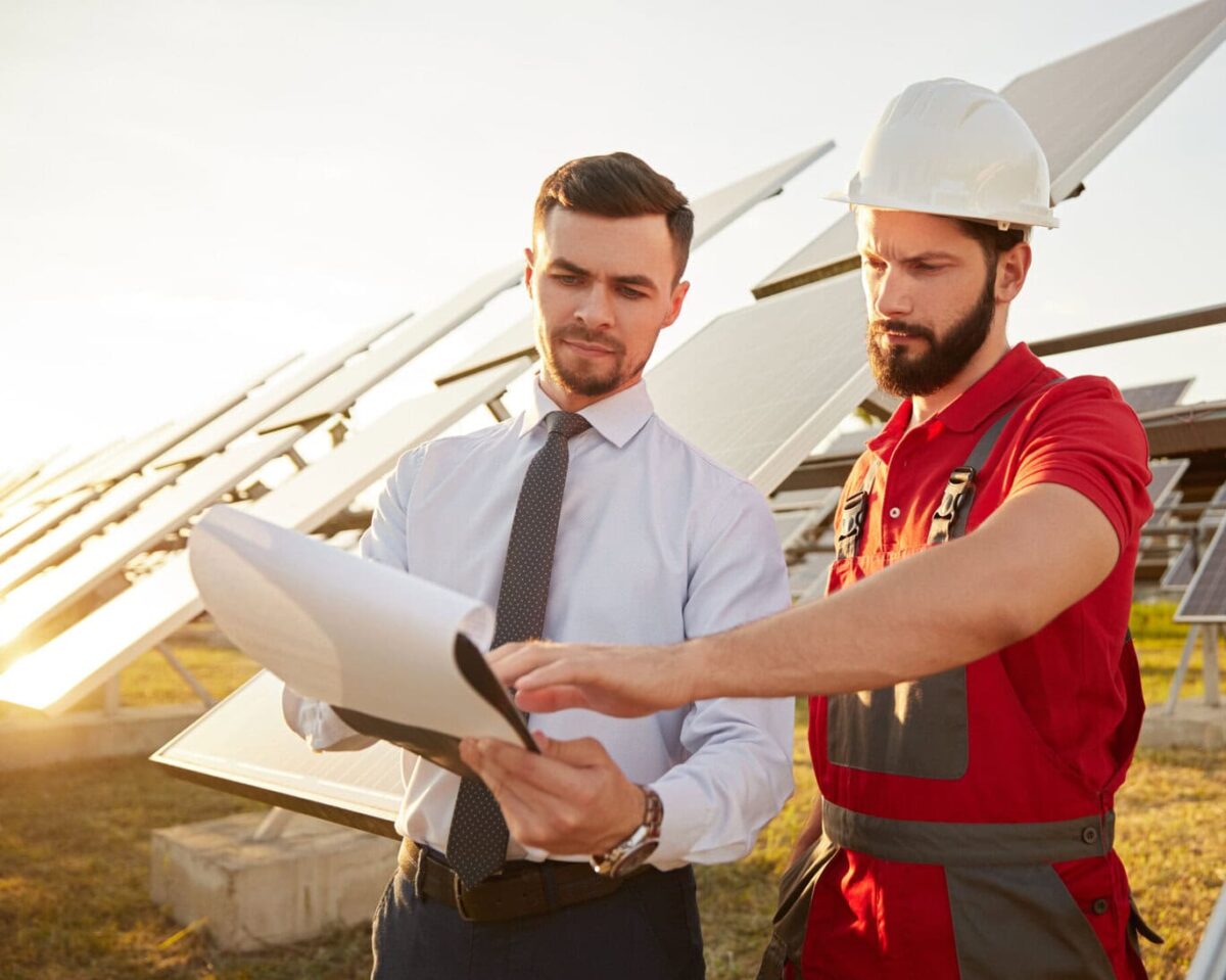 Contractor and manager working in field with solar panels