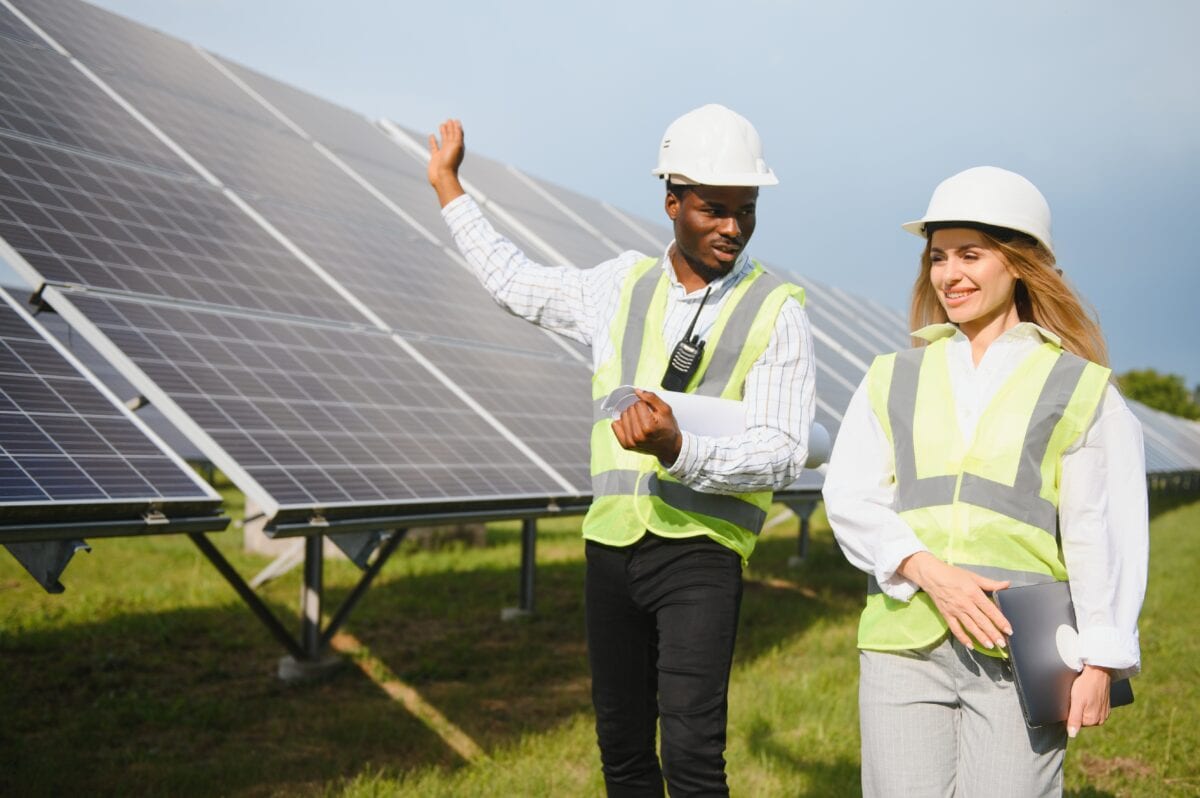 African american businessman and european female engineer talking near solar panels.