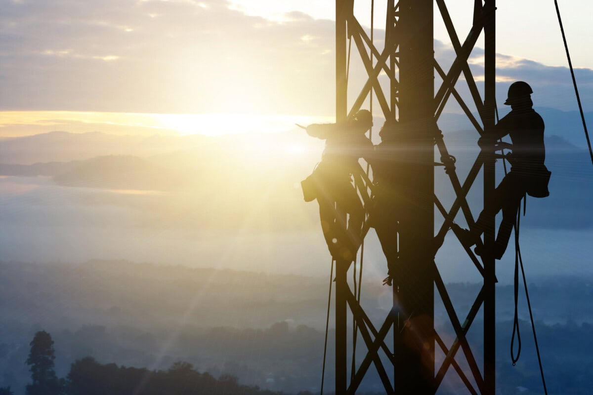 silhouette electrician work on high ground heavy industry concept. construction of the extension of high voltage in high voltage stations safely and systematically over blurred natural background.